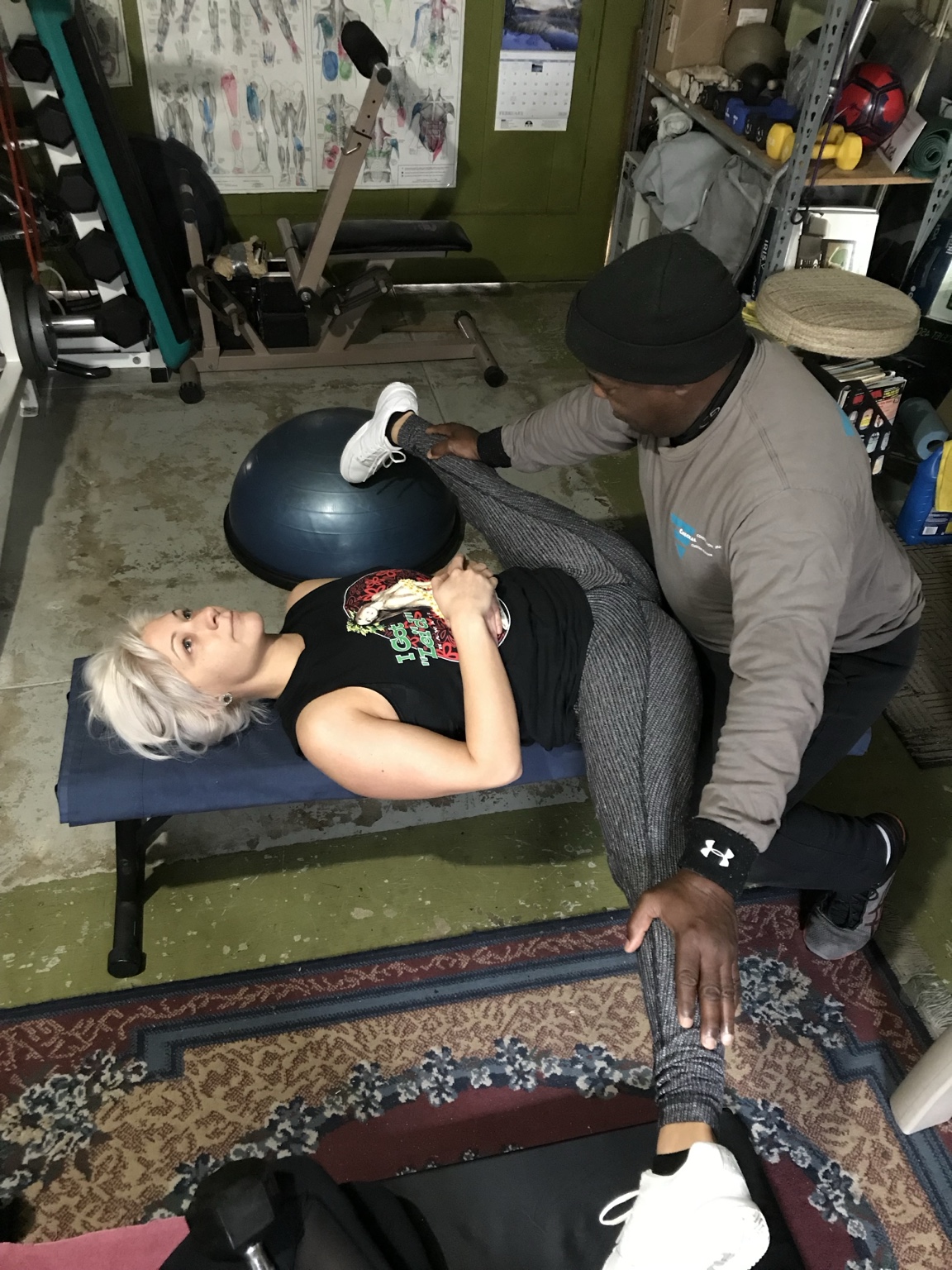 Ken Taylor guiding Hanna Denham through a stretch on a padded bench
