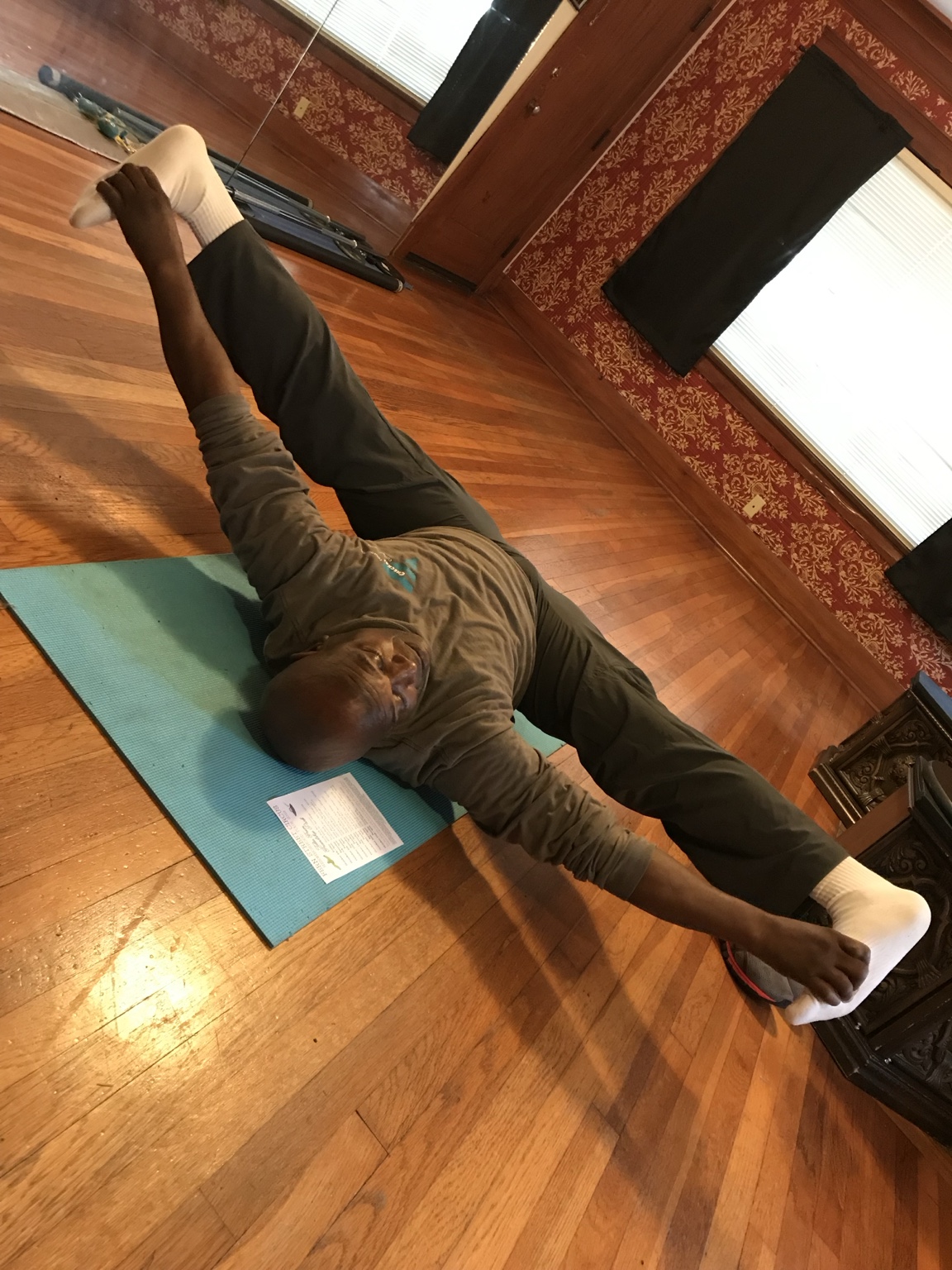 Ken Taylor holding his feet in a wide straddle stretch on a mat