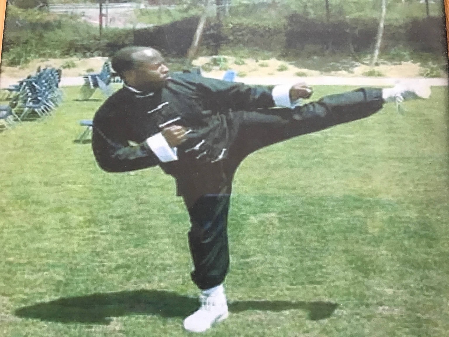 Vintage photograph of Ken Taylor demonstrating a high kung fu kick outdoors